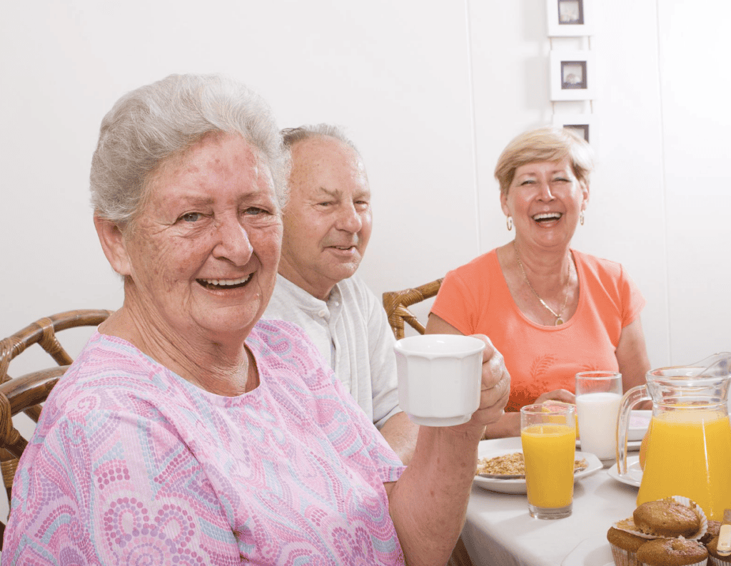 Three seniors enjoying breakfast together at a healthcare facility