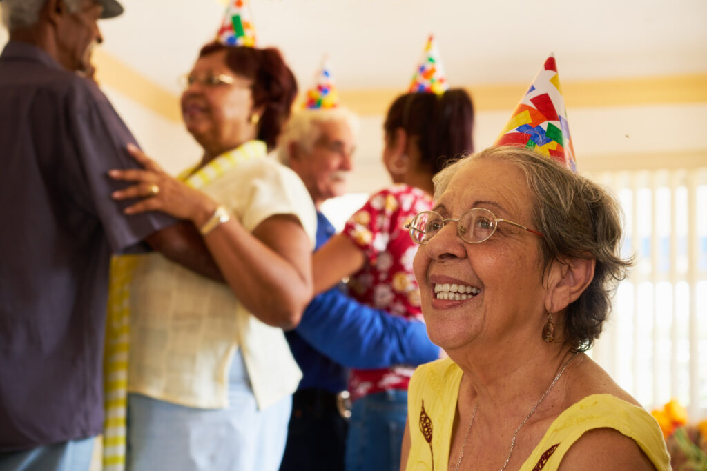 seniors celebrating a birthday party, dancing and wearing birthday hats.