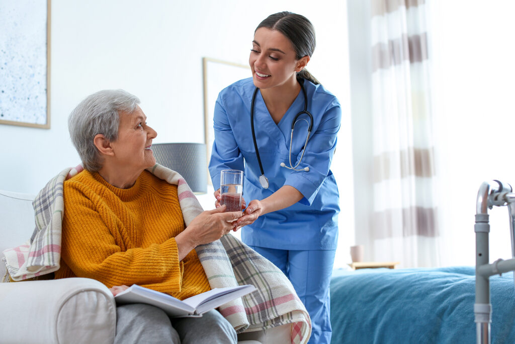 Senior in hospice care receiving water from a nurse practitioner.